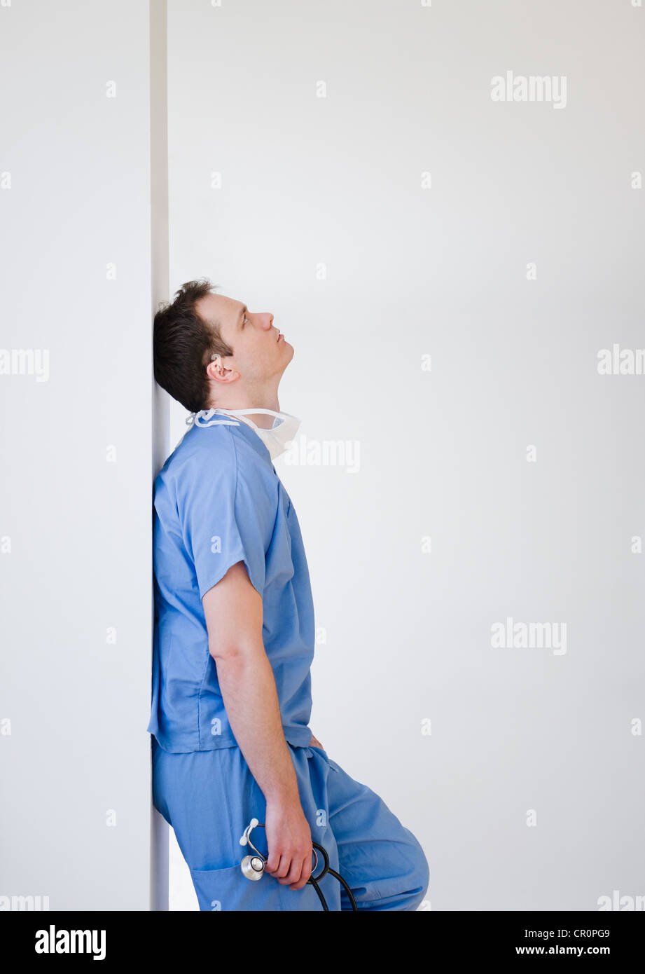 Chirurgo caucasica appoggiata contro la parete Foto Stock