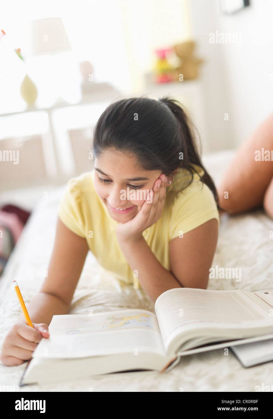 Stati Uniti d'America, New Jersey, Jersey City, ragazza (12-13) giacente sul letto e studiare Foto Stock