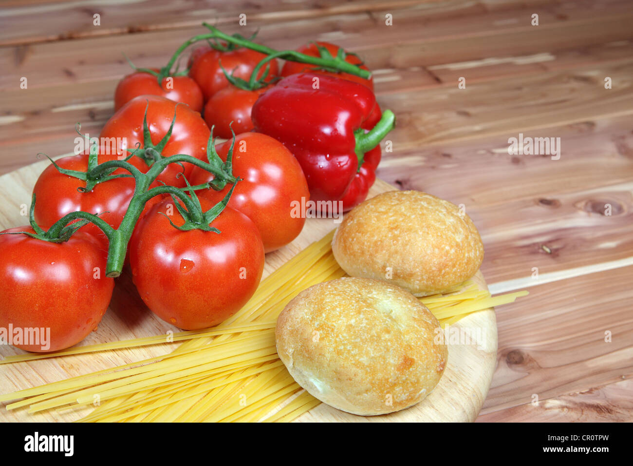 Stile Italiano ingredienti compresi i pomodori, non cotti linguine cipolla e aglio con cena rotoli su un sfondo di legno - con c Foto Stock