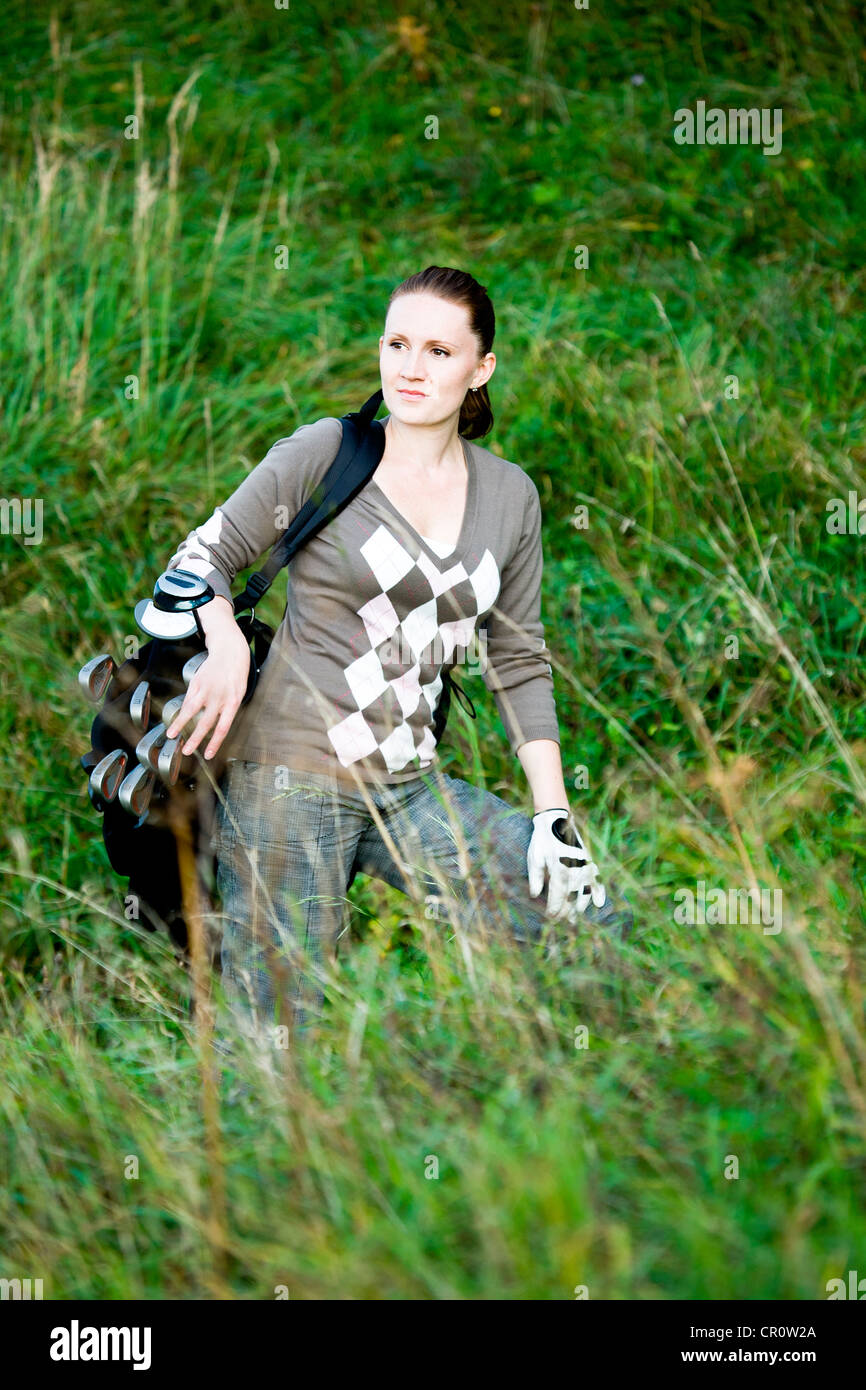 Donna con una sacca da golf, giocando a golf a croce Foto Stock