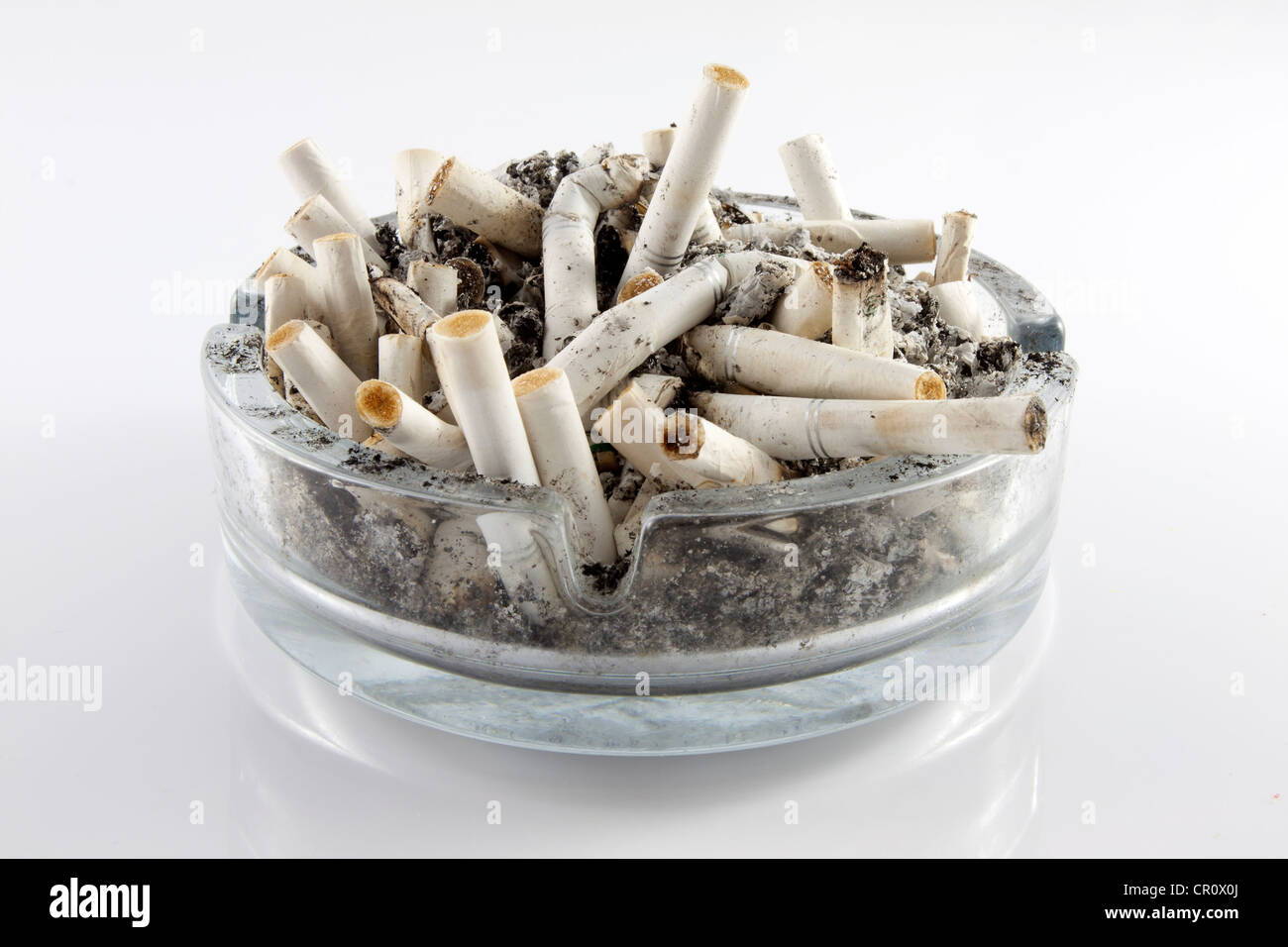 Le sigarette in un posacenere su sfondo bianco Foto stock - Alamy