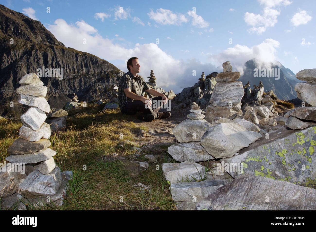 Un uomo meditando tra cairns sul Nufenenpass a 2478m, Canton Vallese, Svizzera, Europa Foto Stock