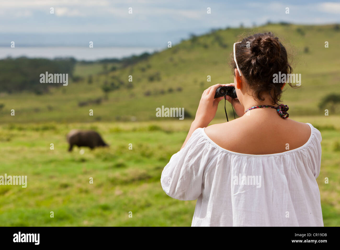 Ragazza, circa 13 anni, guardando un bufalo attraverso il binocolo, Lake Nakuru Lodge, Lake Nakuru National Park, Kenya, Africa orientale Foto Stock