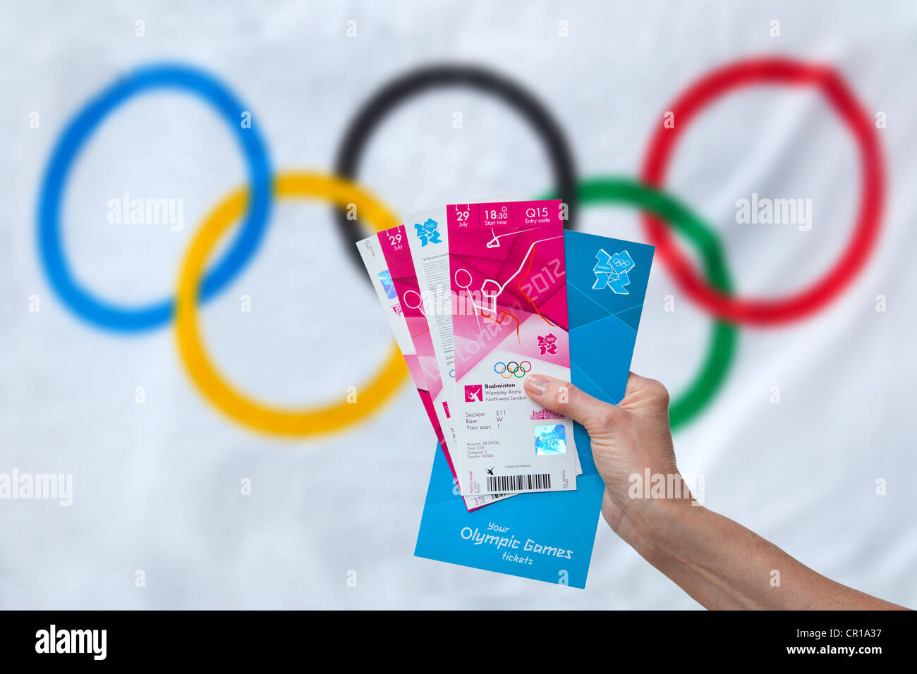Persona che tiene i loro biglietti Olimpico per il London 2012 giochi con la bandiera olimpica in background Foto Stock