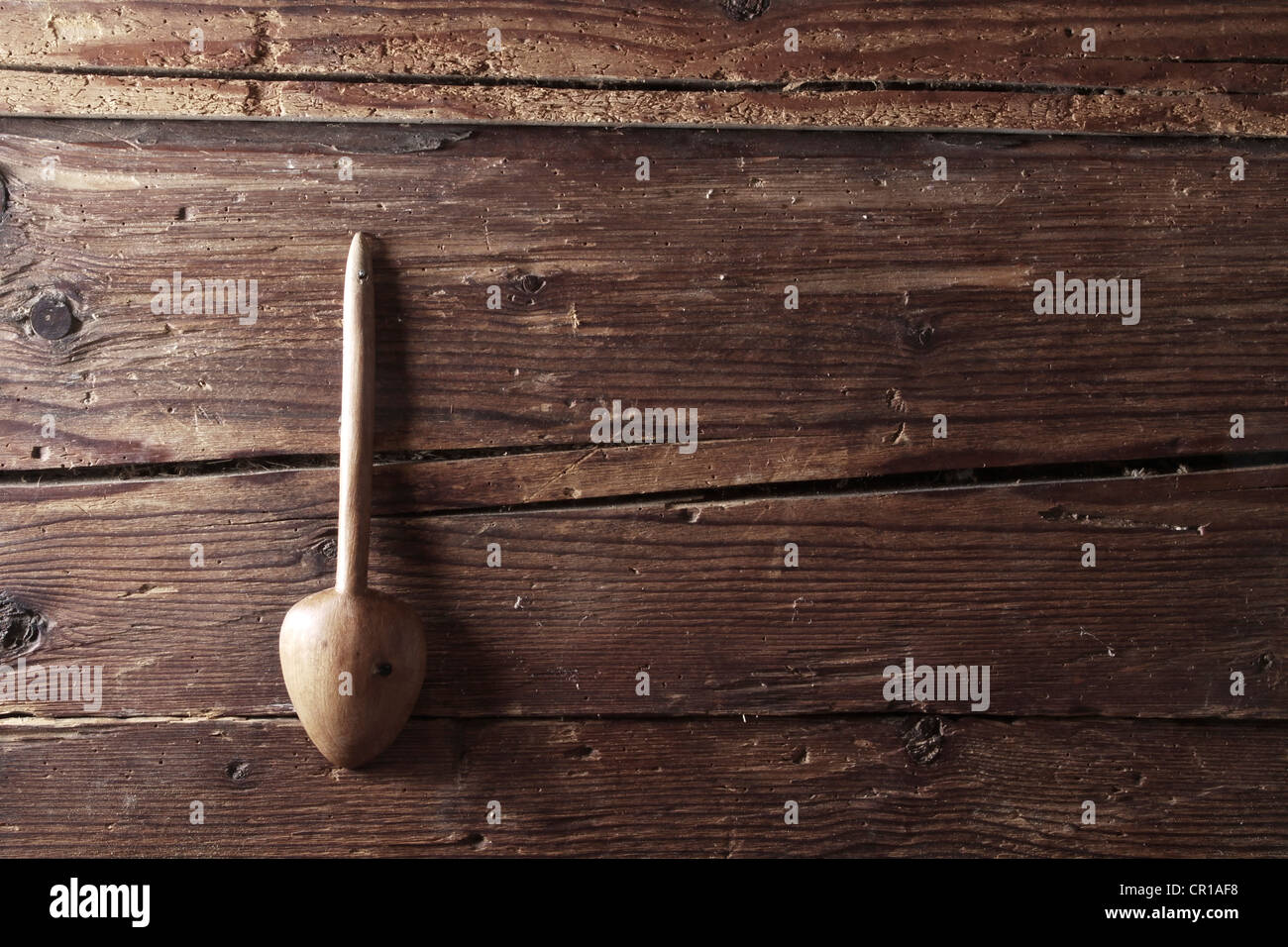 Vecchio cucchiaio di legno sospeso da un rustico parete in legno Foto Stock