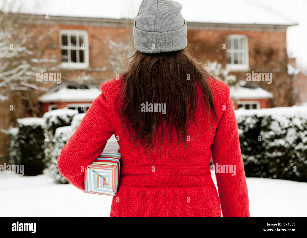 Donna che trasportano dono avvolto nella neve Foto Stock