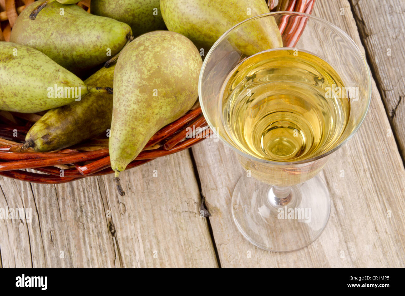 Il vino di frutta in un bicchiere e pere fresche in background Foto Stock