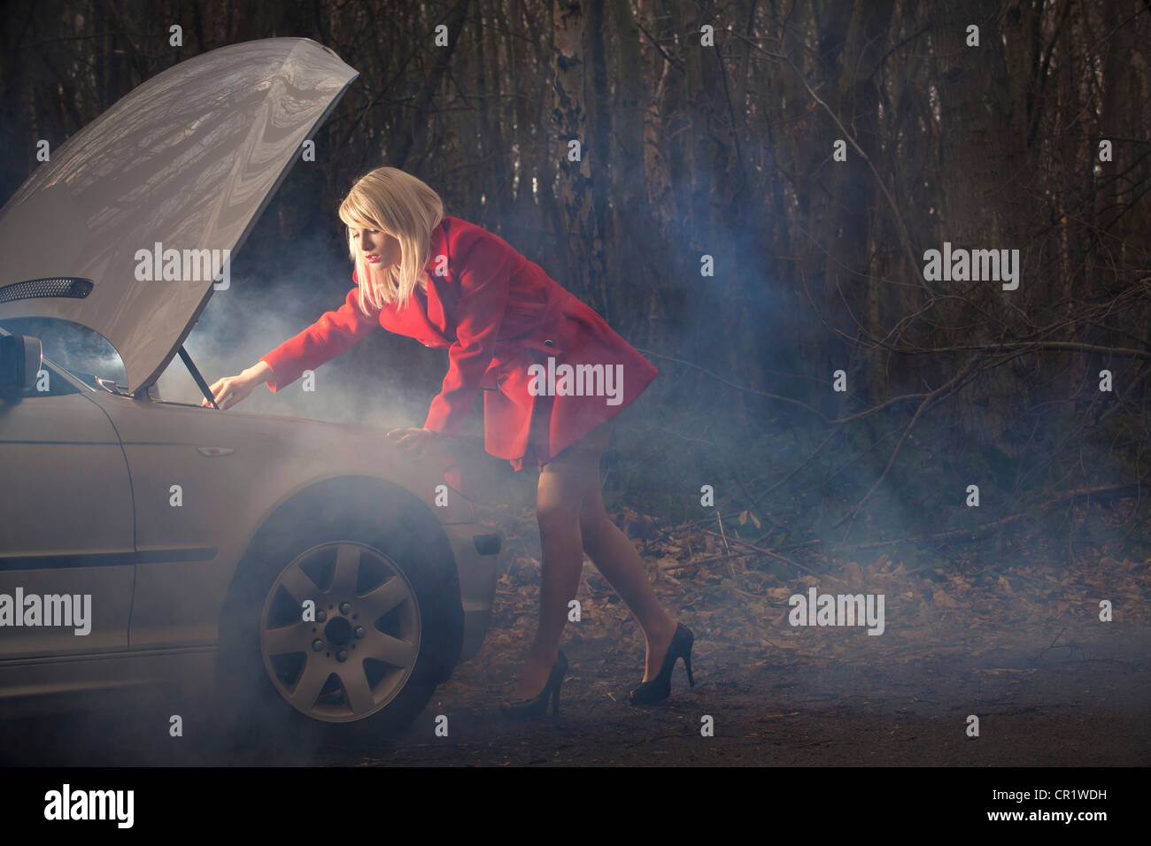 Donna che guarda sotto il cofano della macchina di notte Foto stock - Alamy