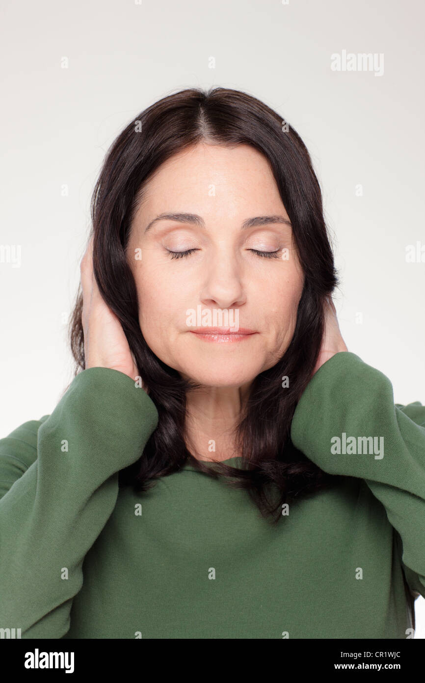 Studio ritratto di donna matura che copre le orecchie Foto Stock