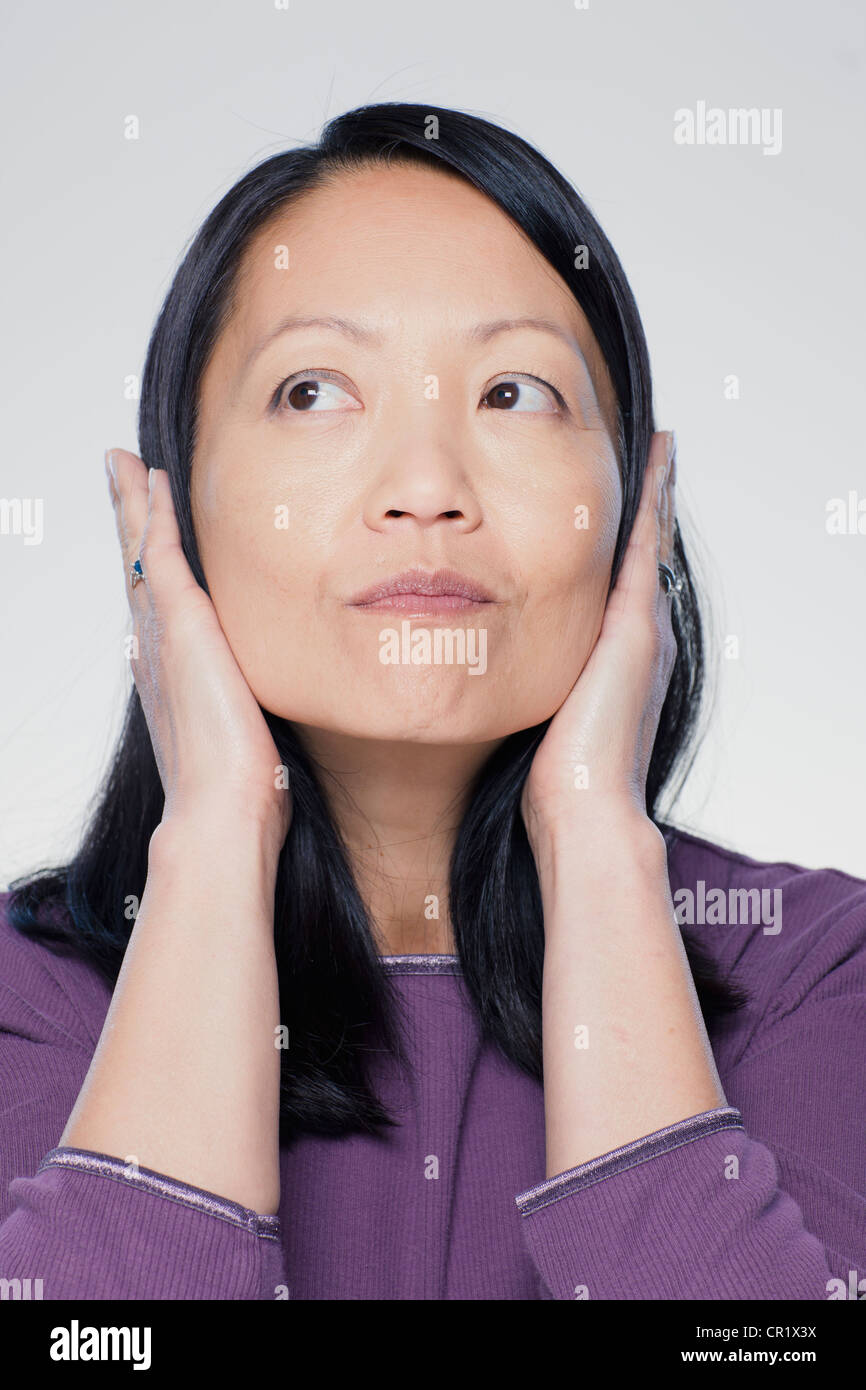 Studio ritratto di donna matura che copre le orecchie Foto Stock