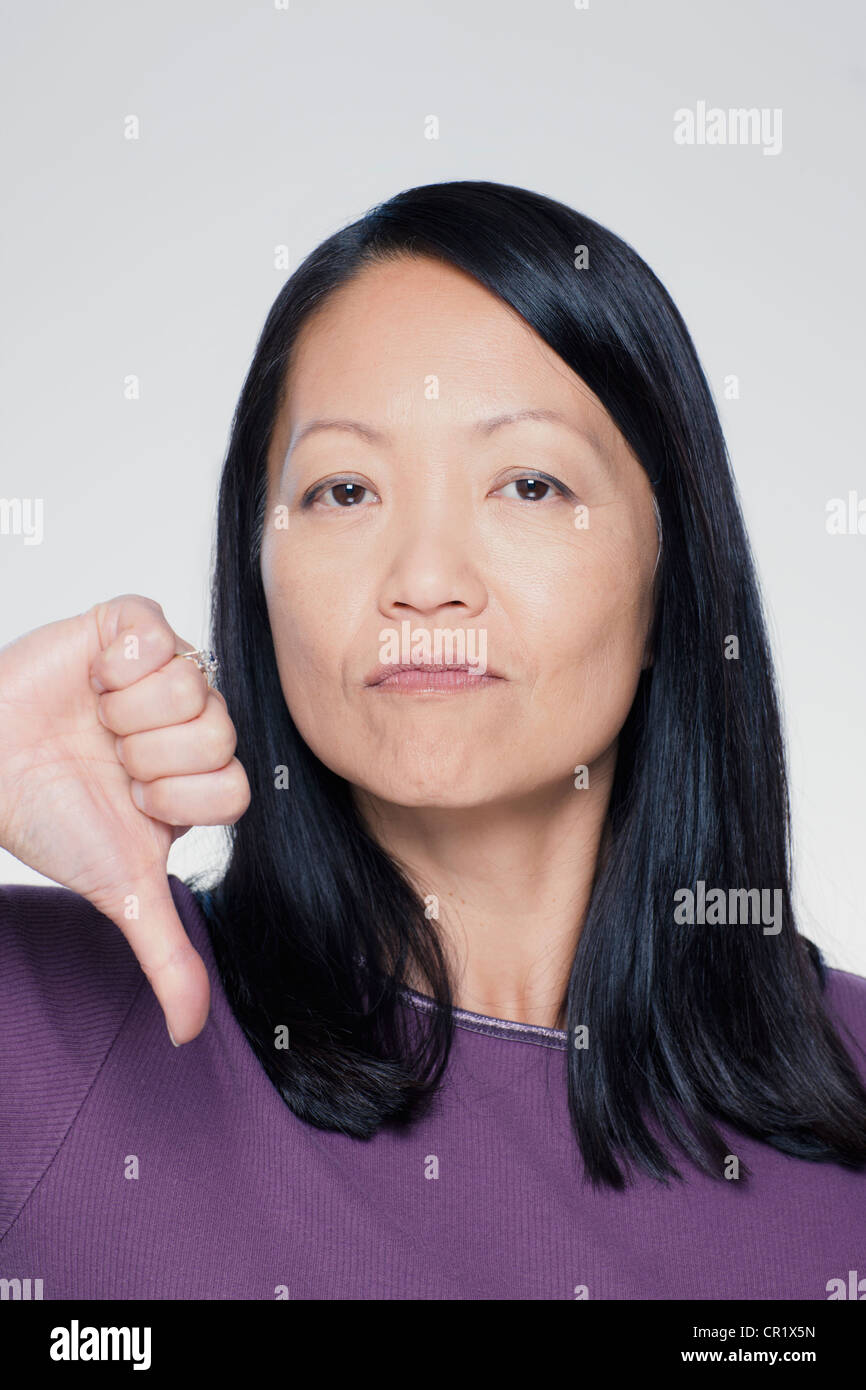Studio ritratto di donna matura che mostra il pollice verso il basso segno Foto Stock