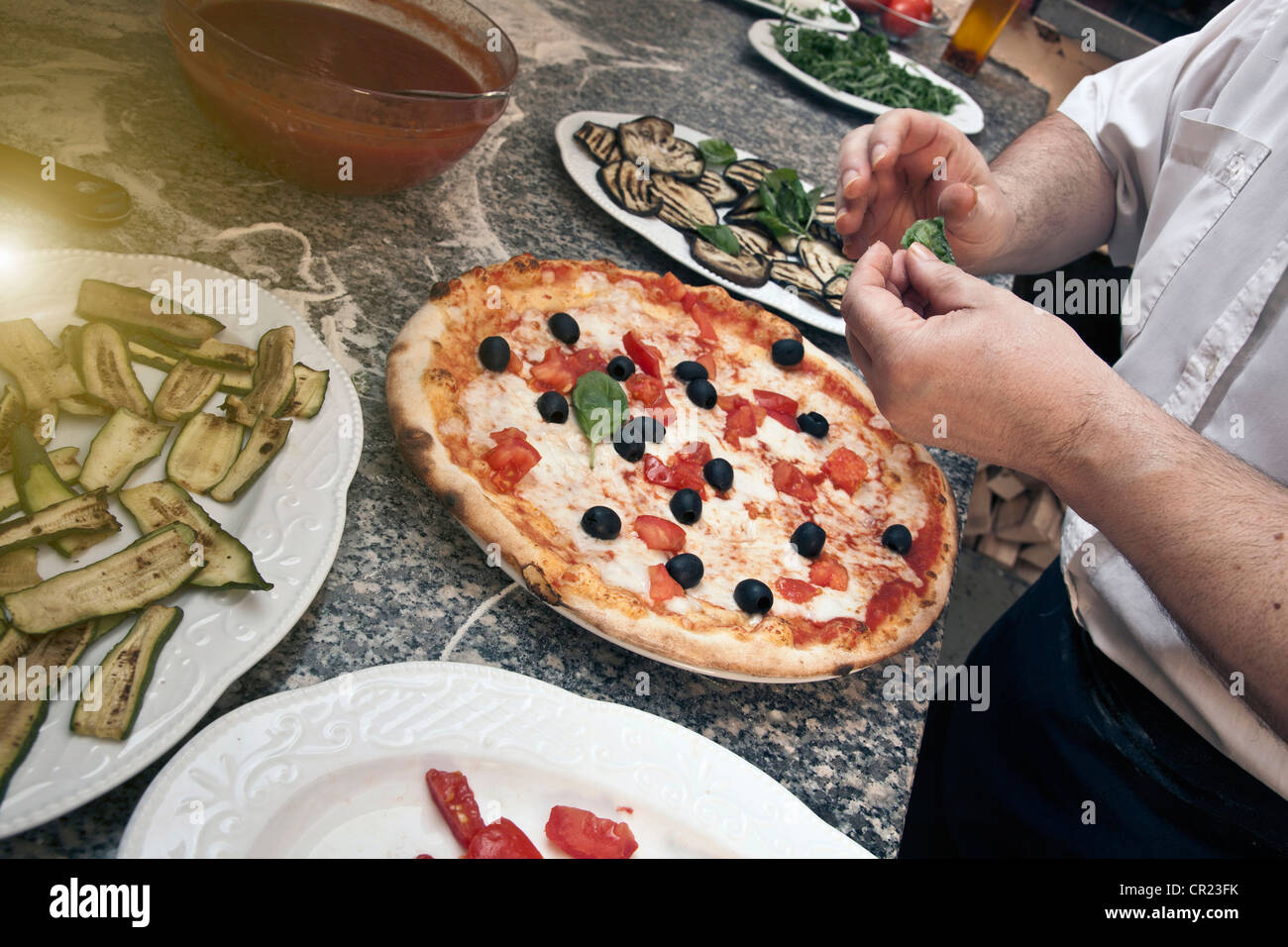 Lo Chef guarnire la pizza in cucina Foto Stock