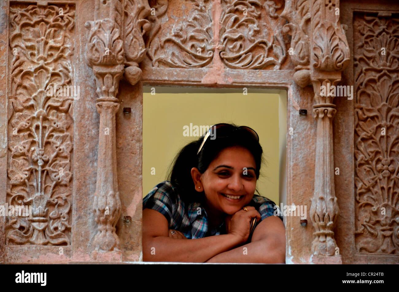 Donna sorridente guardando attraverso la finestra di un palazzo in Rajasthan,l'India Foto Stock