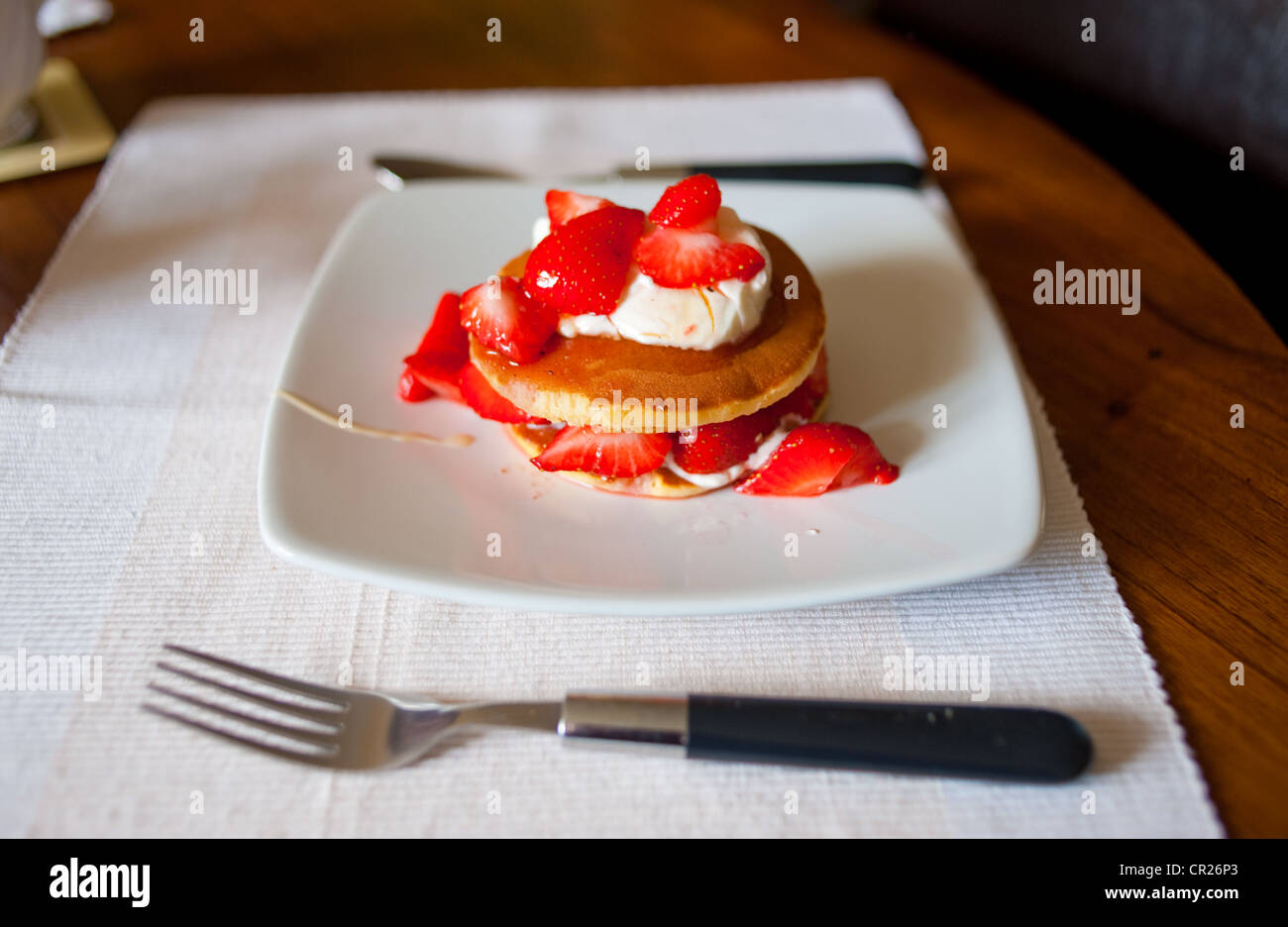 Le fragole servite su pancake con creme fraiche spruzzata con miele per una sana prima colazione Foto Stock