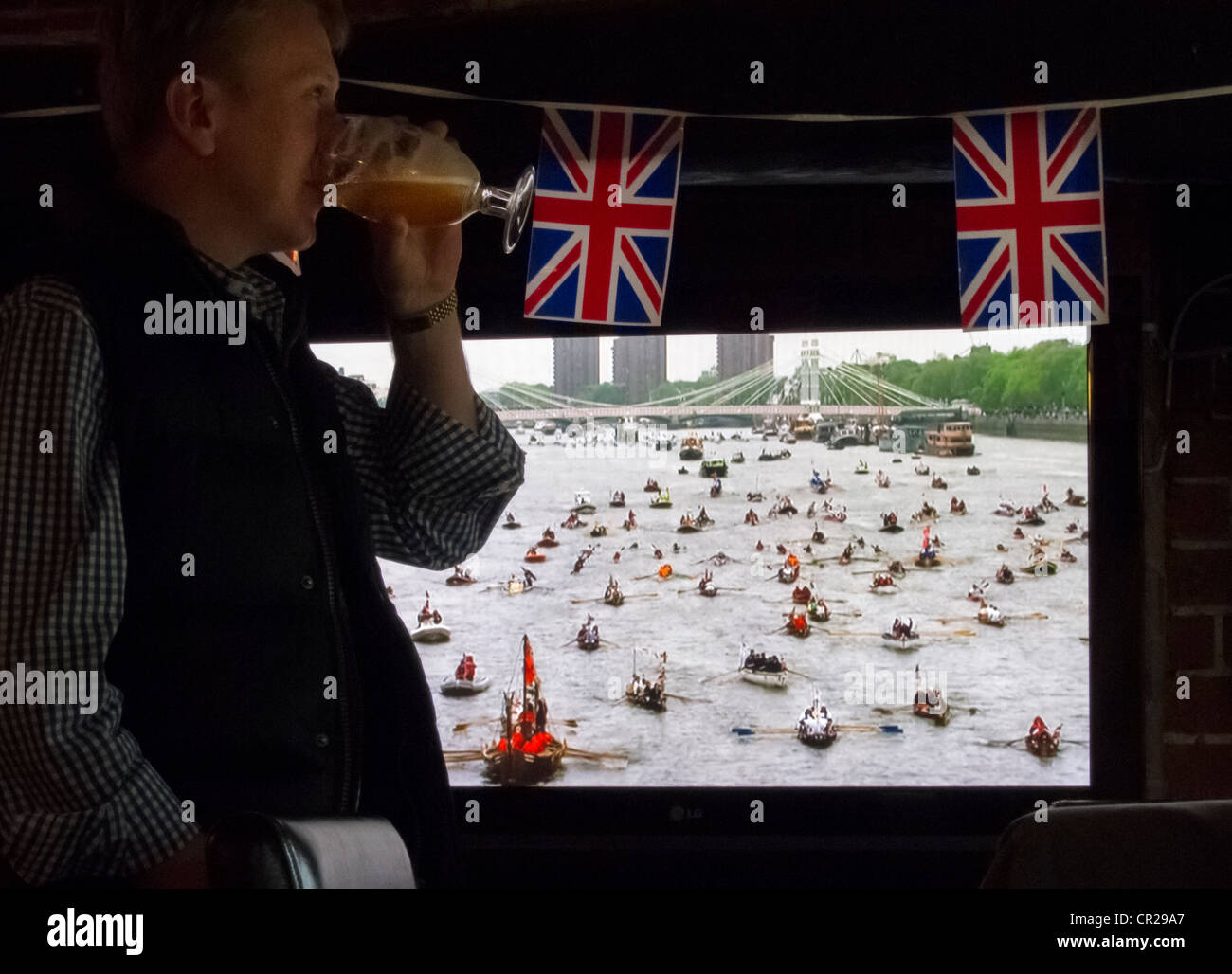 Un uomo beve una pinta di birra durante il Giubileo d oro celebrazioni della Regina Elisabetta II come il fiume Tamigi flottiglia pageant è Foto Stock