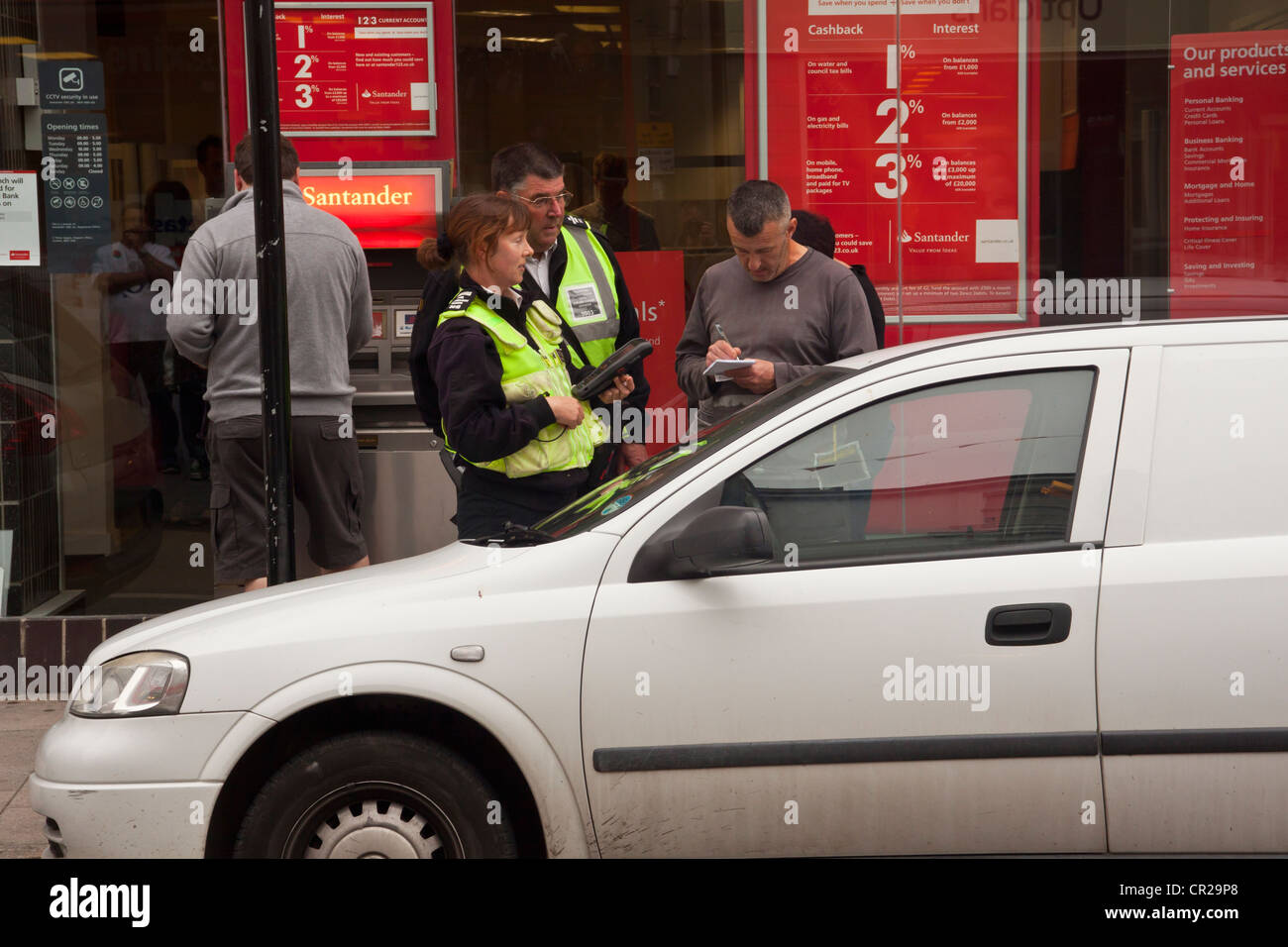 L'uomo sostenendo con il traffico operai sostegno comunitario ufficiali dopo i hes stati dato i biglietti per il parcheggio per il parcheggio è troppo lungo. Foto Stock