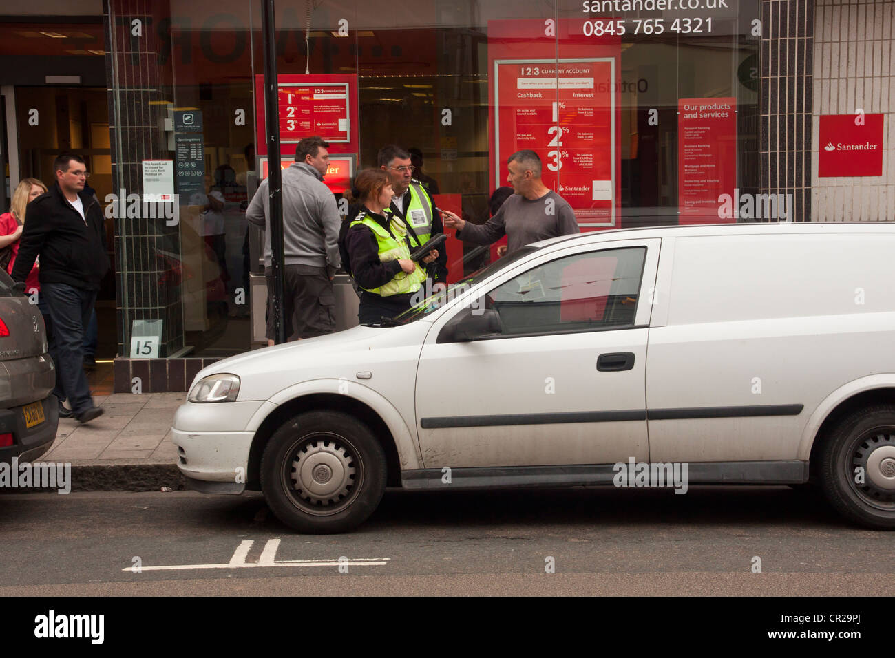 L'uomo sostenendo con il traffico operai sostegno comunitario ufficiali dopo i hes stati dato i biglietti per il parcheggio per il parcheggio è troppo lungo. Foto Stock