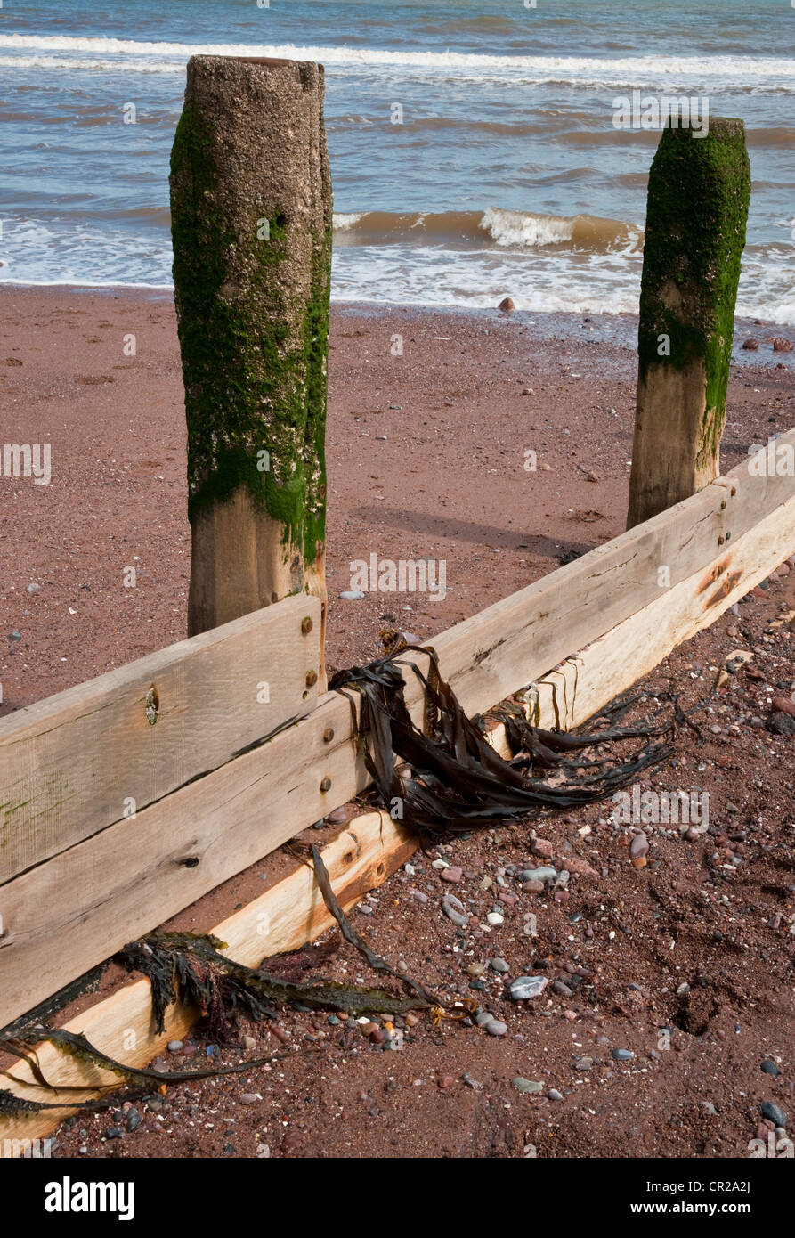 Un vecchio molo in legno proteso sul mare da una spiaggia di sabbia. Foto Stock