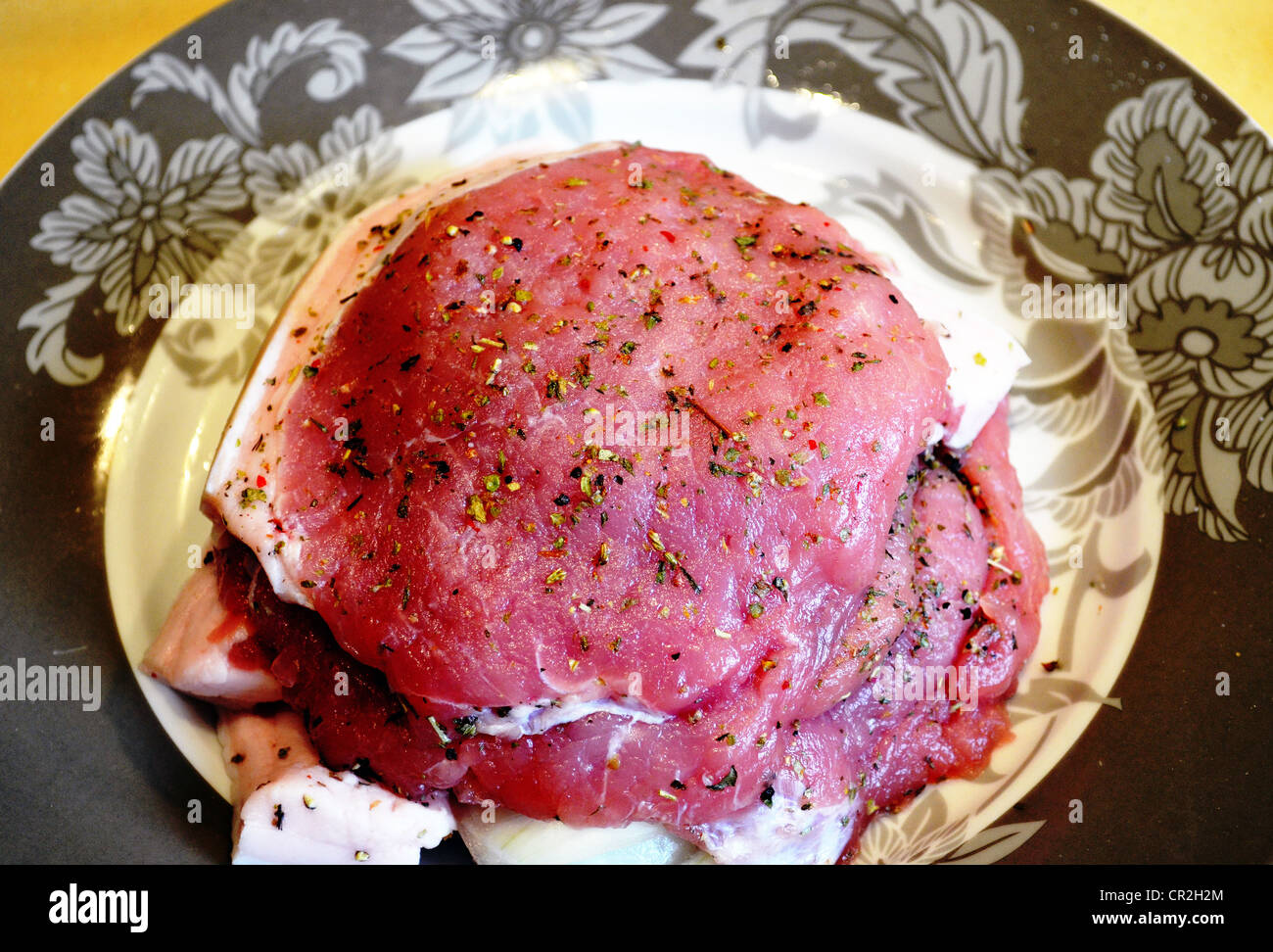 Tagliare a fette costolette di maiale bistecche con spezie antigoccia preparato per la cottura nel piatto. Foto Stock