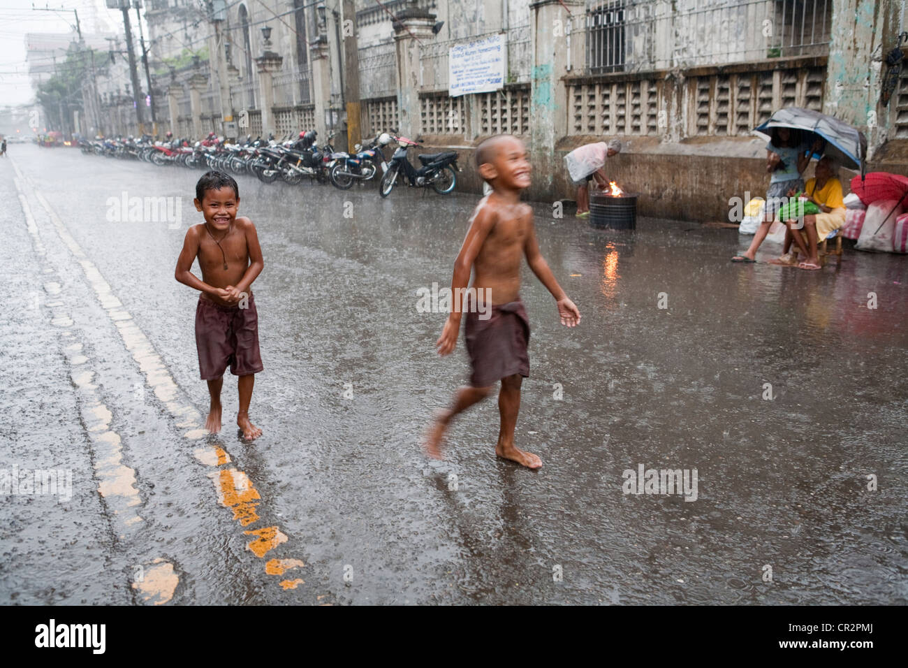 Cebu City, Filippine, 11.Marzo 2012: bambini filippini divertirsi durante un acquazzone come la stagione di pioggia arriva alla fine. Foto Stock