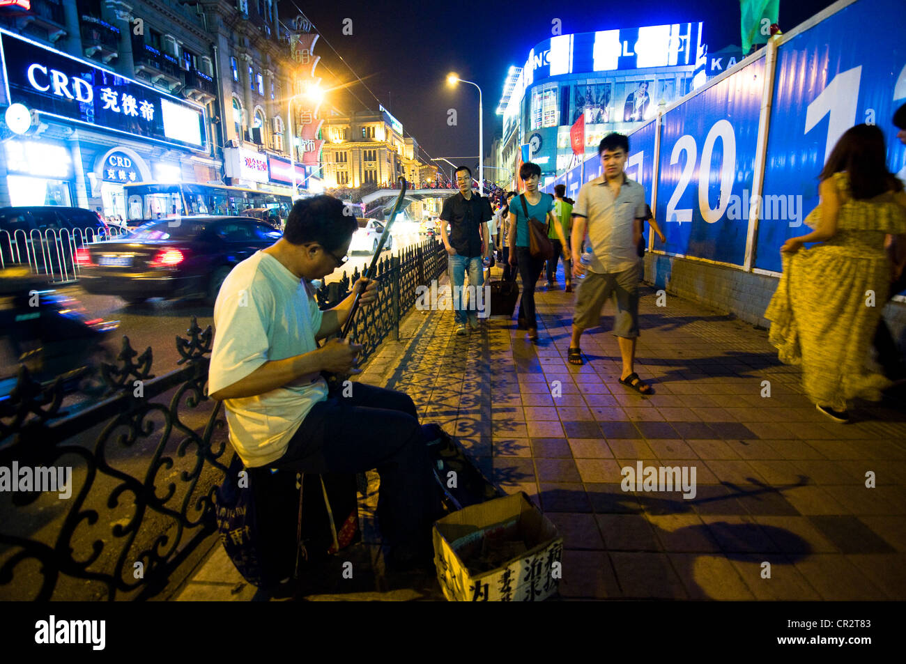 Un uomo cinese la riproduzione di musica tradizionale cinese durante le ore di notte in una strada trafficata a Wuhan, Cina. Foto Stock