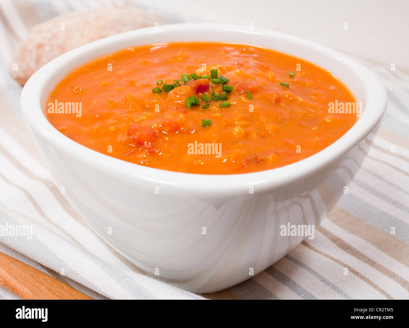 Una ciotola di lenticchie e zuppa di pomodoro guarnita con erba cipollina. Foto Stock