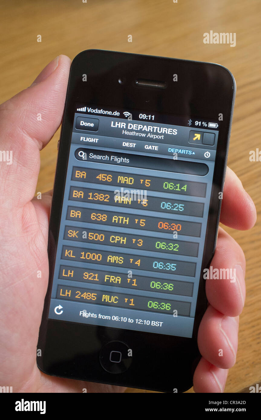 Uomo con tracking voli App per guardare live flight scheda partenze presso l'aeroporto di Heathrow su un iPhone 4G Foto Stock