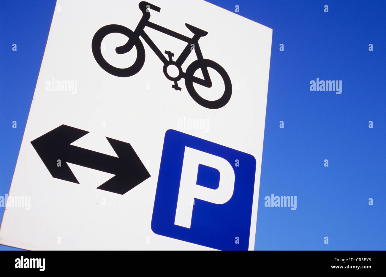 Bianco nero e blu segno contro il cielo blu con icona di bicicletta e le frecce che indicano dove possono essere parcheggiate Foto Stock
