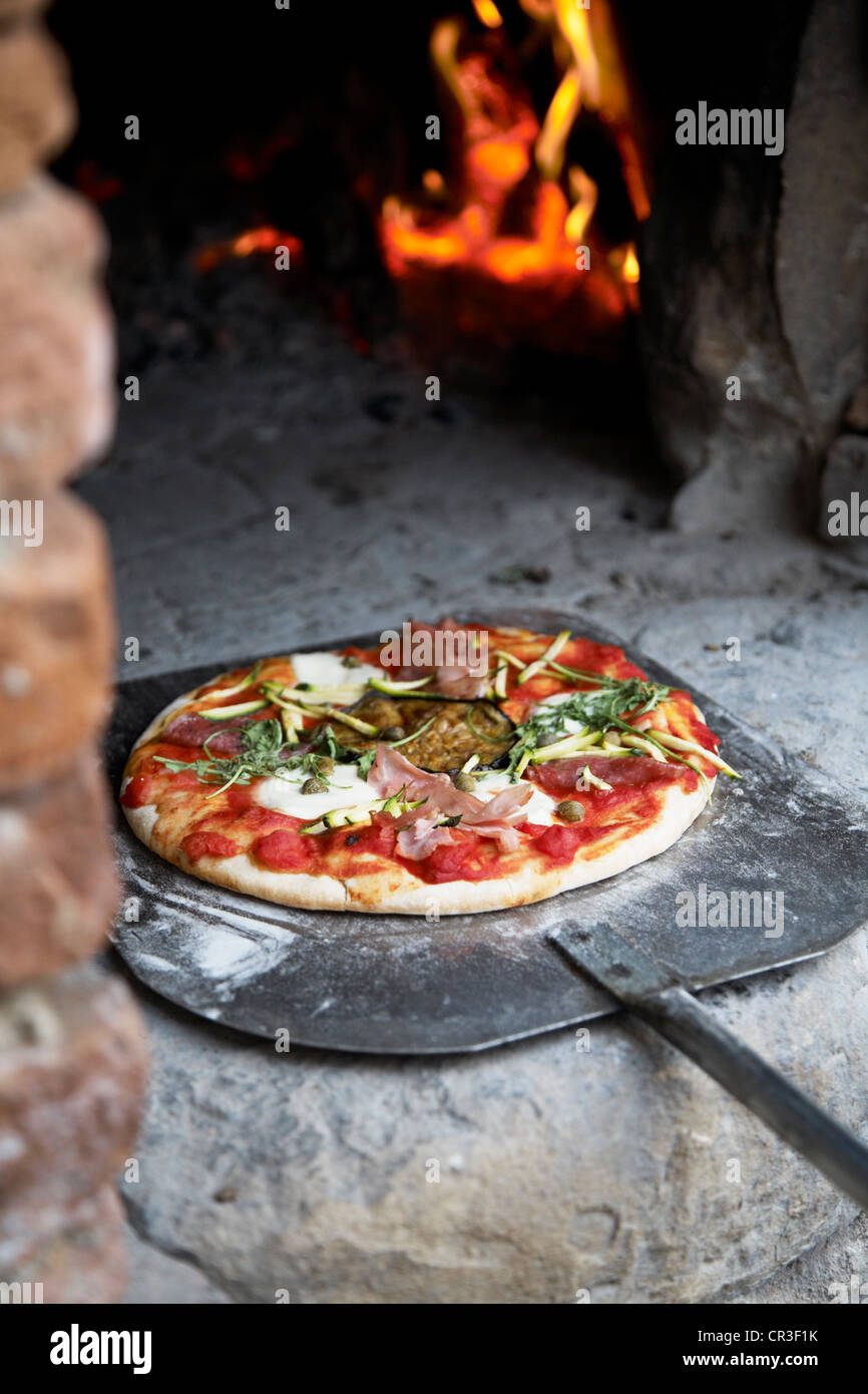 Un pane appena sfornato pizza in uscita di un tradizionale a legna per forno  in pietra su una paletta di pizza Foto stock - Alamy