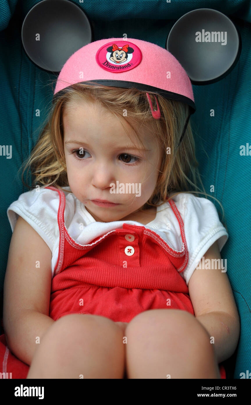 Bambina esausta in passeggino con il cappello rosa Topolino