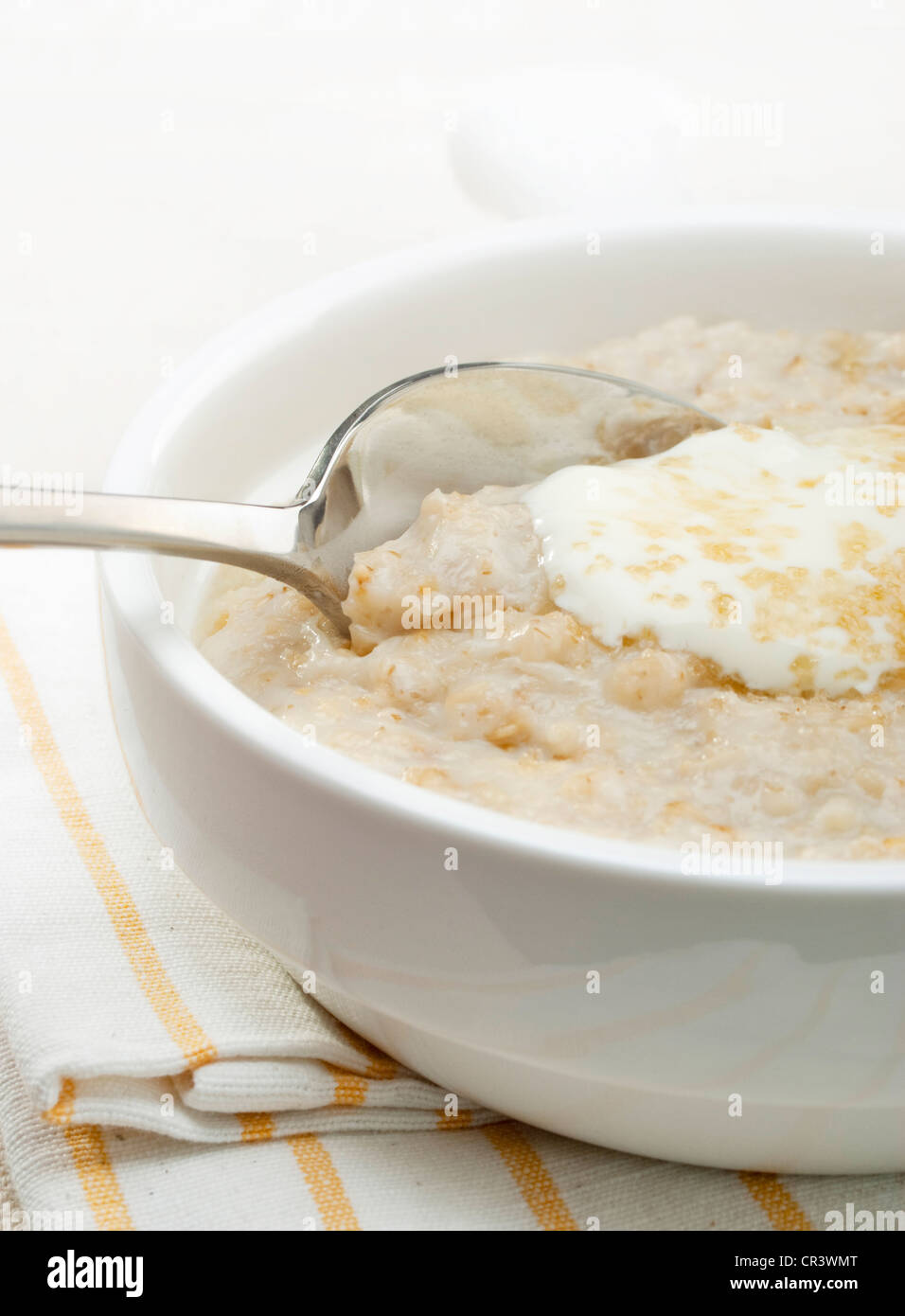 Il Porridge di avena per la prima colazione o un nutriente spuntino economico, guarnita con yogurt e zucchero di canna. Foto Stock