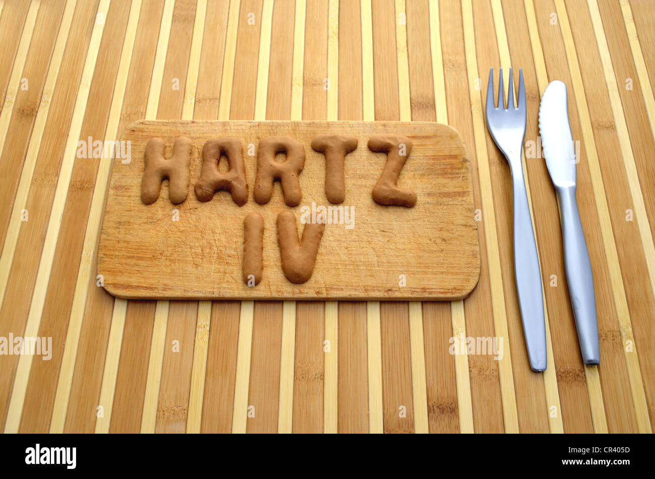 Hartz IV, Tedesco il sostegno al reddito, scritto in lettere dal pane russo cookie sul legno vassoio colazione, posate, coltello, forchetta Foto Stock