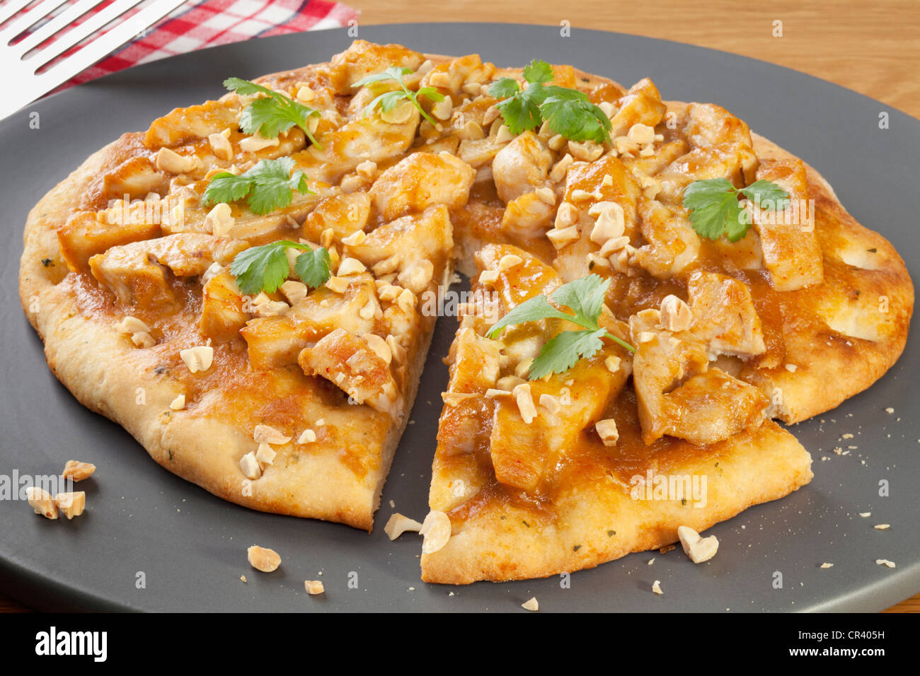 Pizza con pollo satay, guarnita con coriandolo e arachidi tostate. Foto Stock