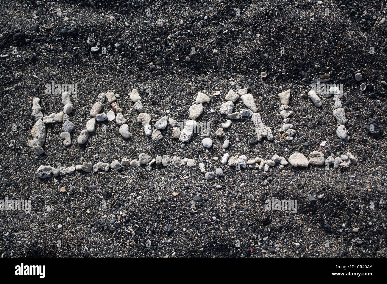 Hawaii parola scritta in corallo bianco sulla spiaggia di sabbia nera Foto Stock