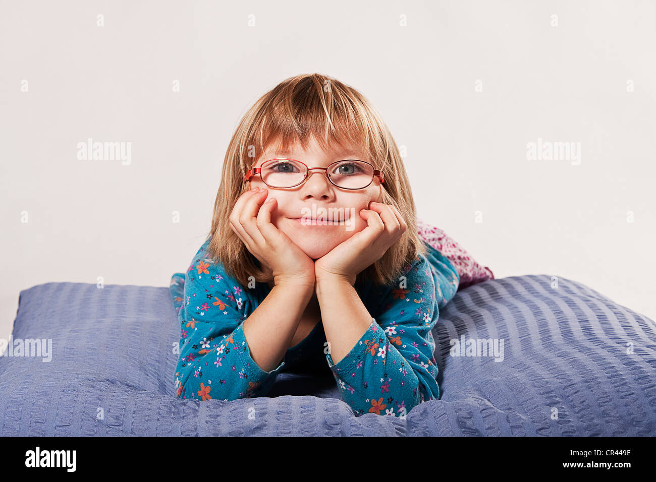 Ragazza con gli occhiali che giace su di un cuscino Foto Stock
