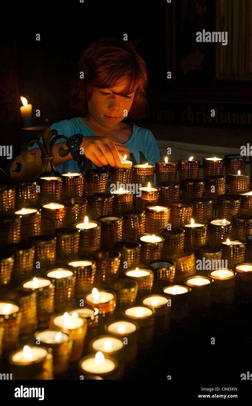Bambino di illuminazione votiva di una candela in una chiesa, la Cattedrale di San Pietro, Cattedrale di Worms, Worm, Renania-Palatinato, Germania, Europa Foto Stock