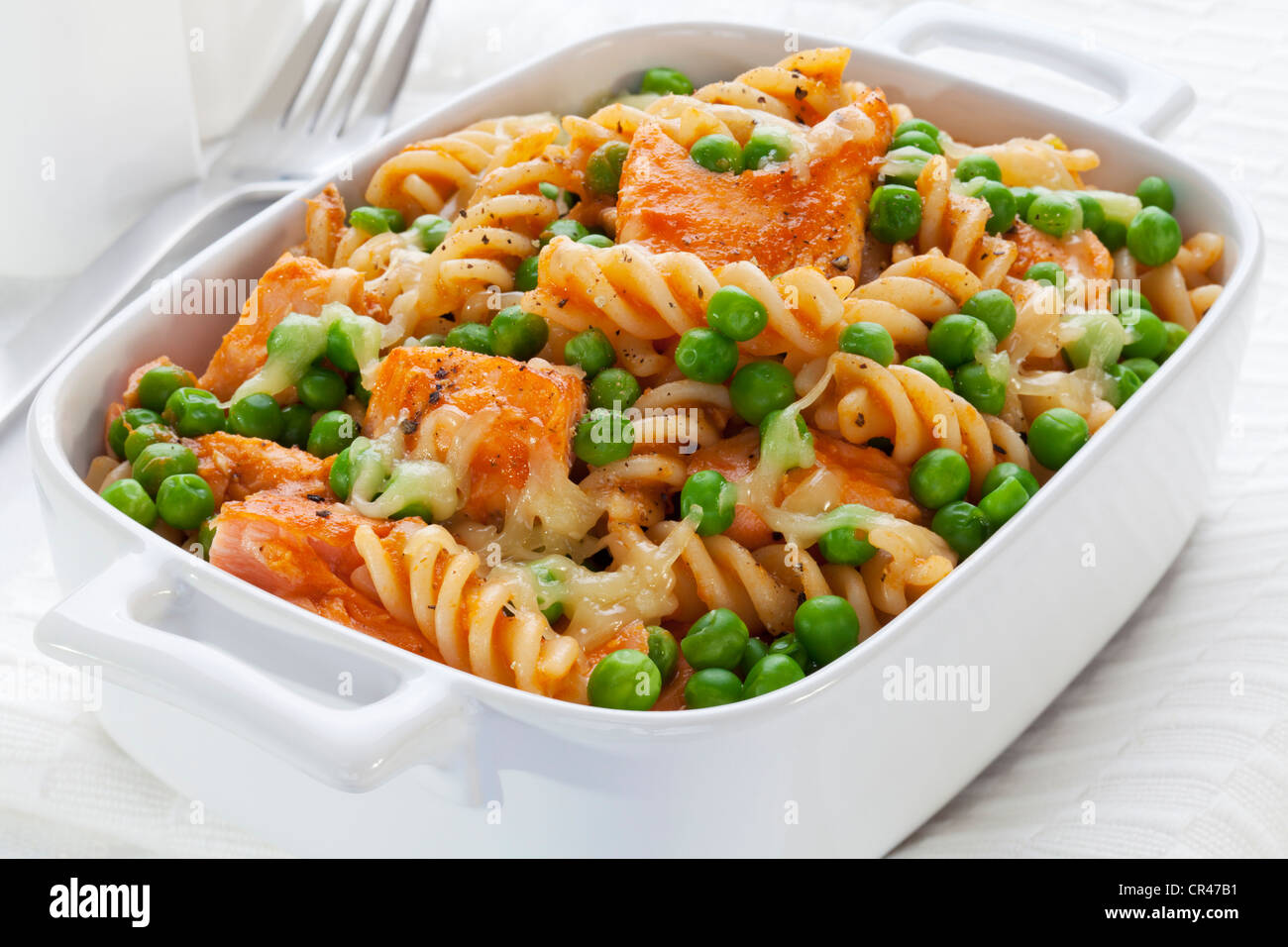 Un piatto al forno di fusili o a spirale, pasta con salmone alla griglia, piselli e mozzarella. Foto Stock