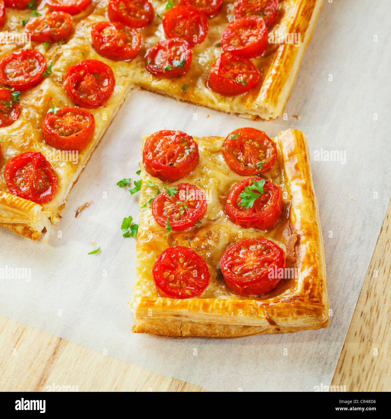 Crostata di pomodoro, pasta sfoglia guarnita con la senape, formaggio e ciliegia toamtoes. Foto Stock