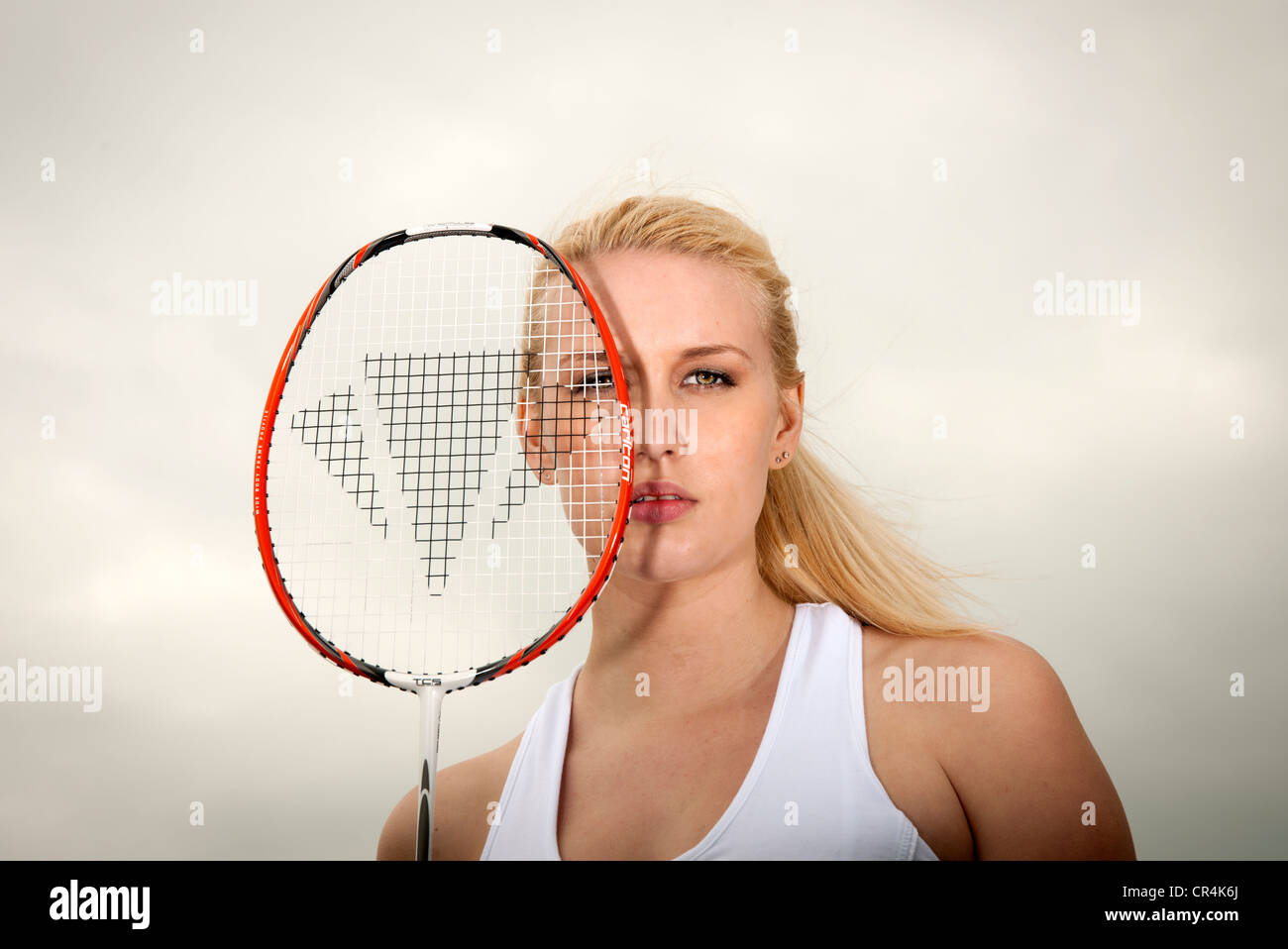Donna che mantiene badminton racchetta nella parte anteriore del suo viso Foto Stock