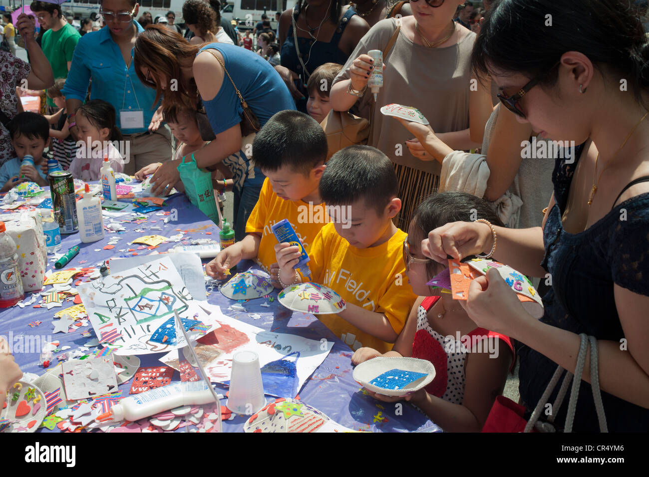 Un gruppo multietnico di bambini decorare yarmulkes in Eldridge Street Sinagoga di un uovo di creme e rotoli di uovo Street Fair Foto Stock