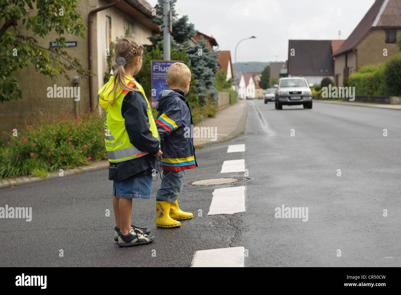 Due bambini di 3 e 7 anni, in attesa di attraversare la strada, Assamstadt, Baden-Wuerttemberg, Germania, Europa Foto Stock