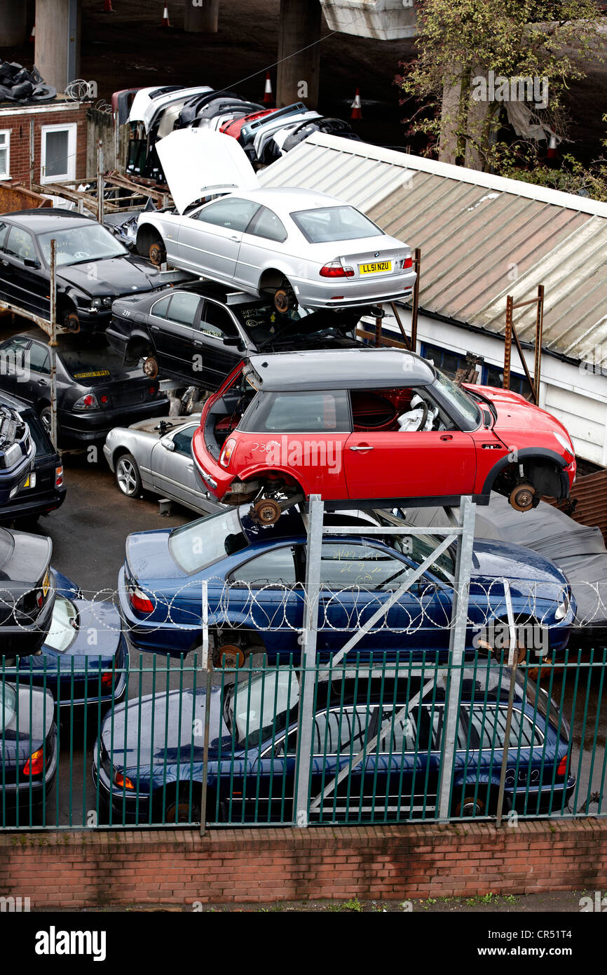 I rottami di automobili attendono lo smantellamento di una vettura breakers cantiere. Il metallo viene riciclato e quindi fatta in diversi prodotti Foto Stock