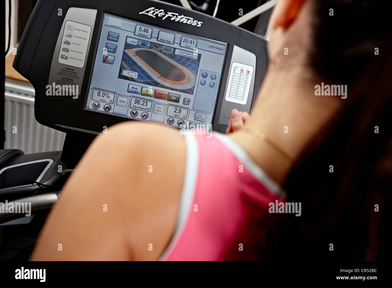 Una signora in una palestra su una macchina da corsa. Pic mostra virtual partner in esecuzione il display della console. Foto Stock