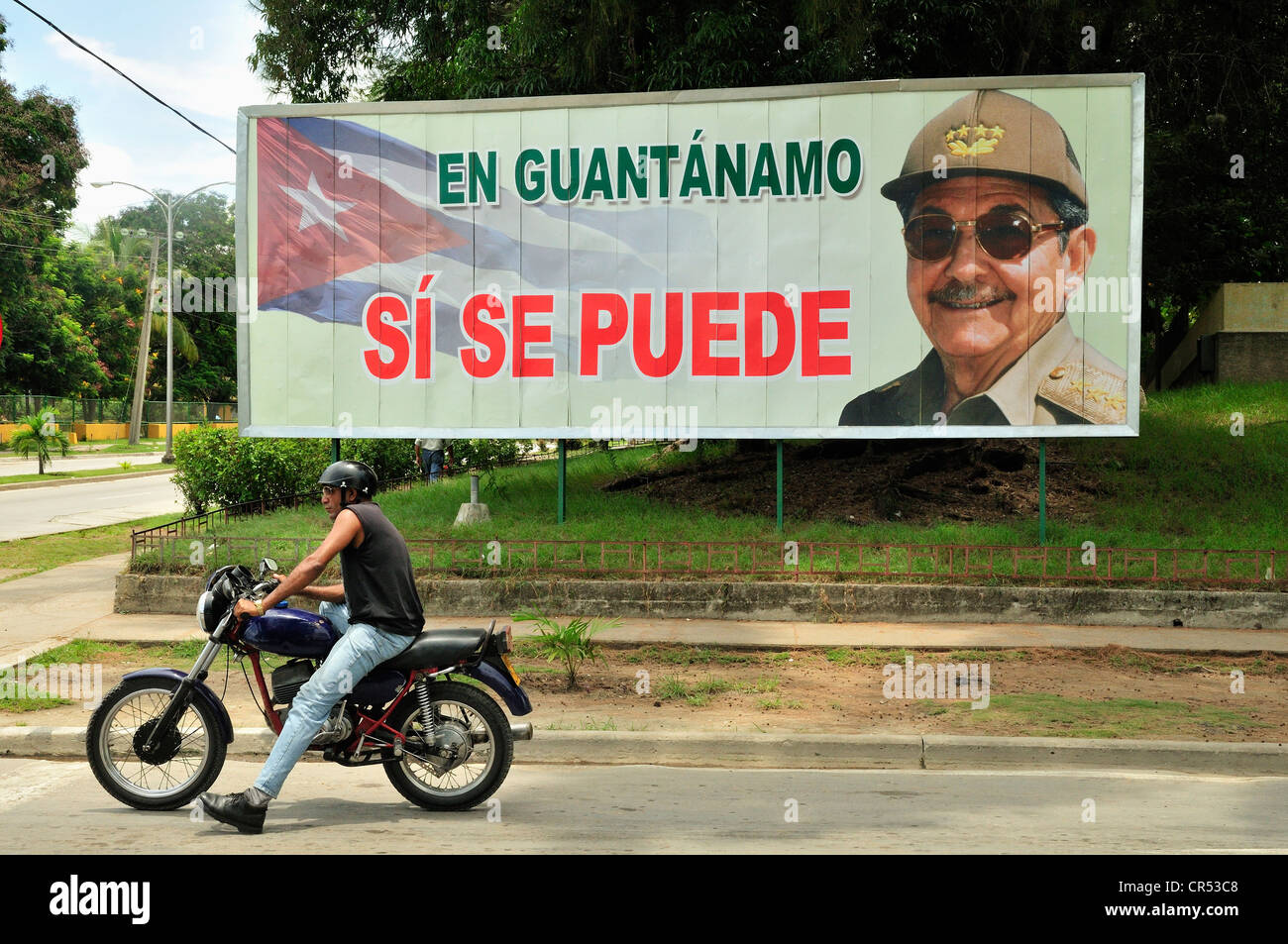 Motociclista di fronte un segno con la propaganda rivoluzionaria, En Guantánamo si se puede, a Guantánamo, a Cuba, dei Caraibi Foto Stock