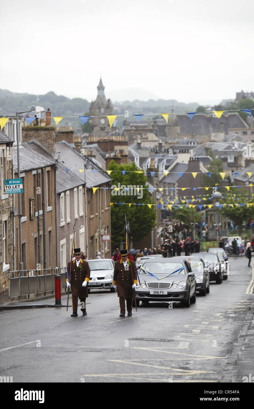 Alabardieri portano la processione di vip in auto sulla strada per il Moro durante Hawick Common-Riding nella città di confine, Scozia Foto Stock