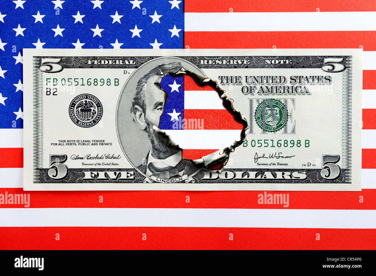 Bruciato cinque-dollaro su una bandiera americana, immagine simbolica per il debito nazionale degli Stati Uniti Foto Stock