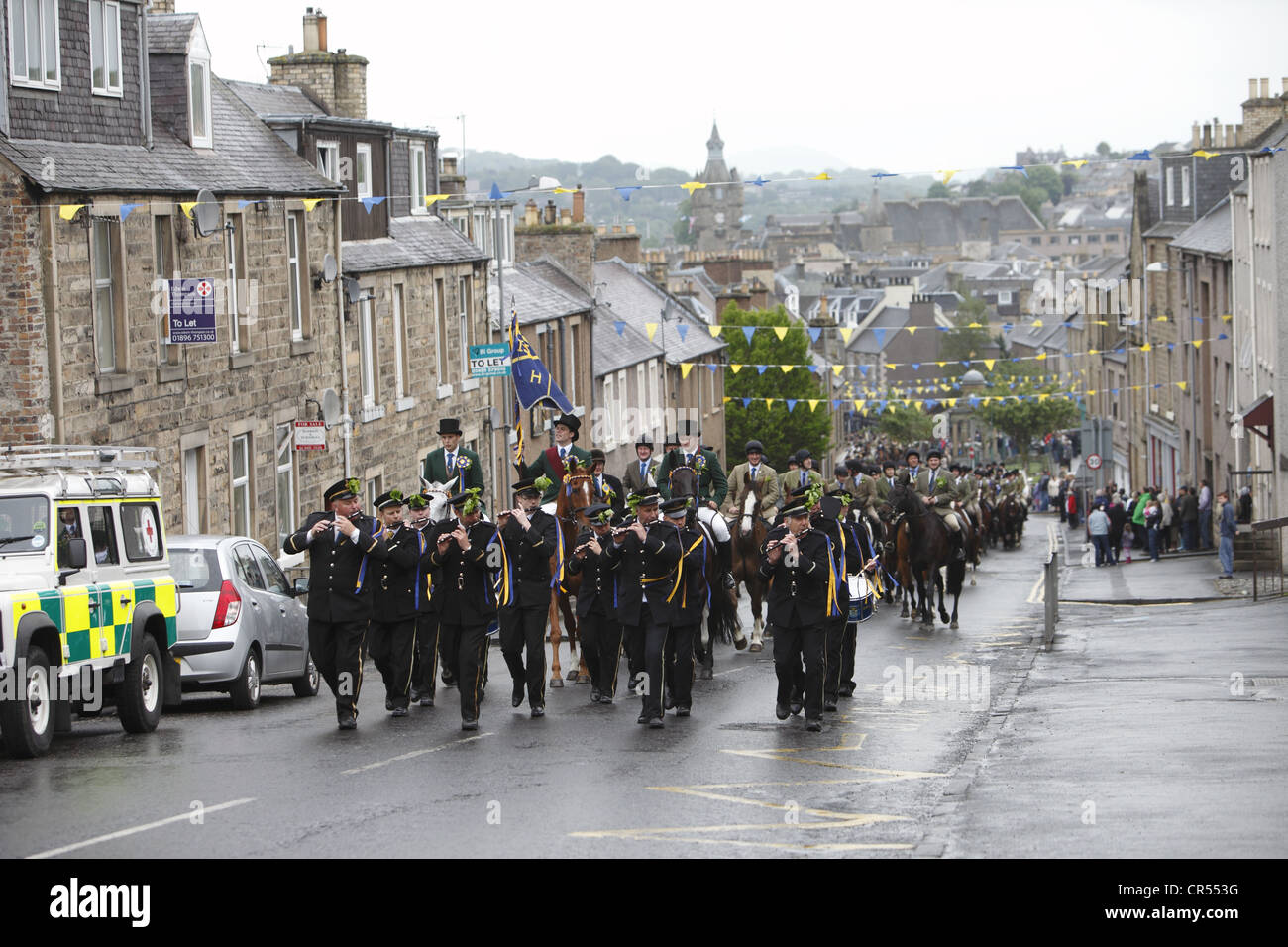 La Cornet e sostenitori seguire dietro Drum & Fife band per il Moro durante Hawick Common-Riding nella città di confine, Scozia Foto Stock