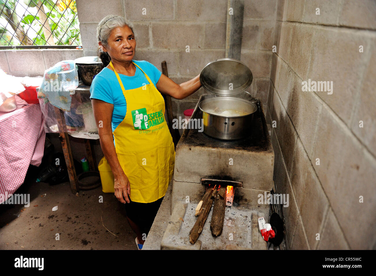 Cuoca sollevando il coperchio di una pentola per la cottura su un risparmio energetico stufa, comunità di Cerro Verde, El Salvador, America Centrale Foto Stock