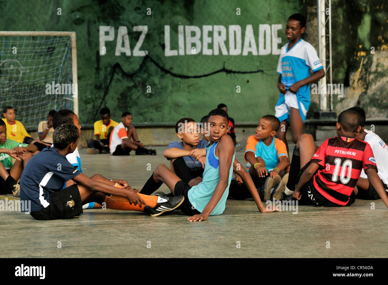 Gli adolescenti e i bambini in un parco giochi, a parete con caratteri "Paz Liberdade', Portoghese per 'pace libertà' sul retro Foto Stock