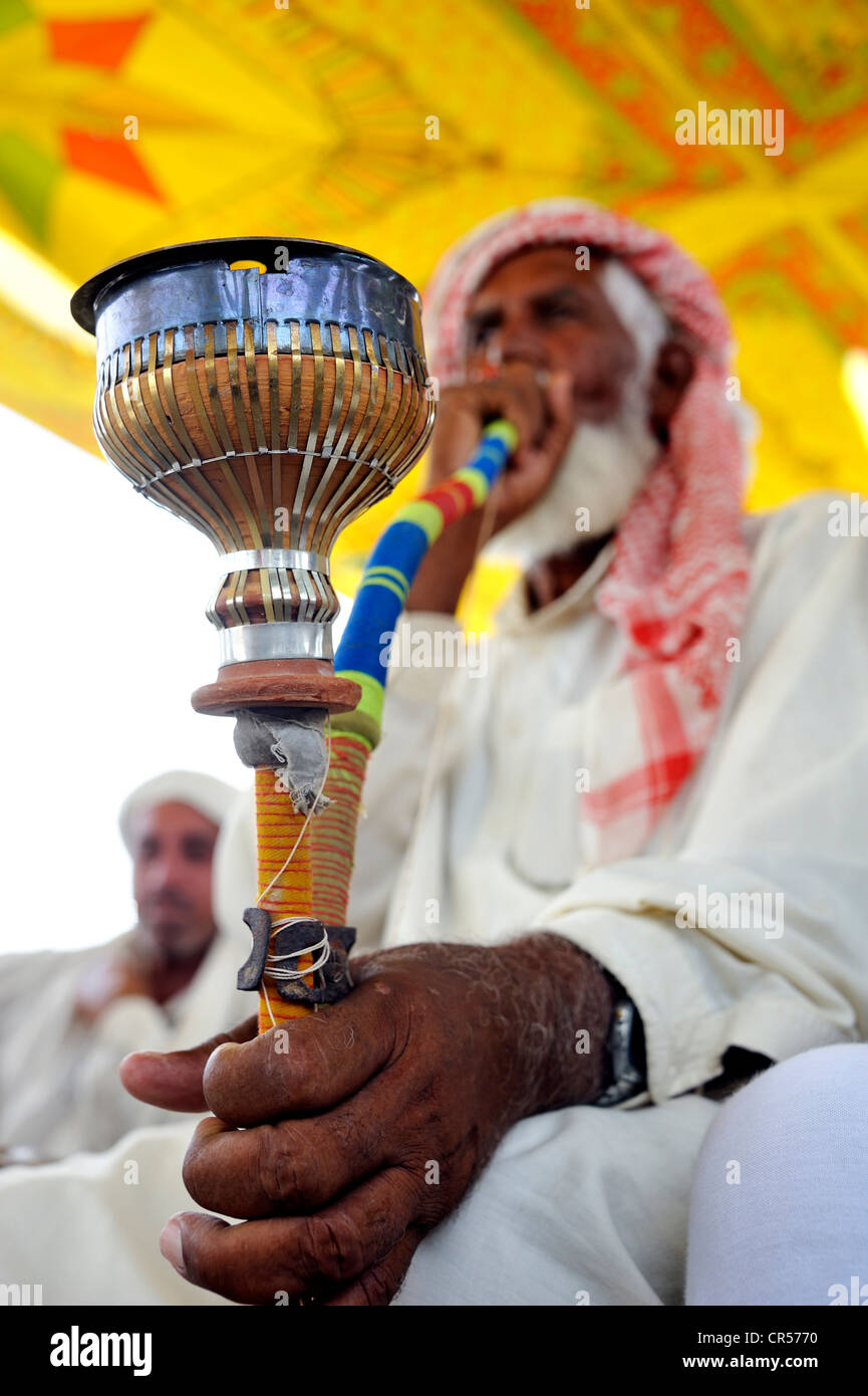 Uomo anziano con la barba bianca, il tabacco da fumo in un tradizionale tubo, waterpipe, Muzaffaragarh Punjab, Pakistan, Asia Foto Stock
